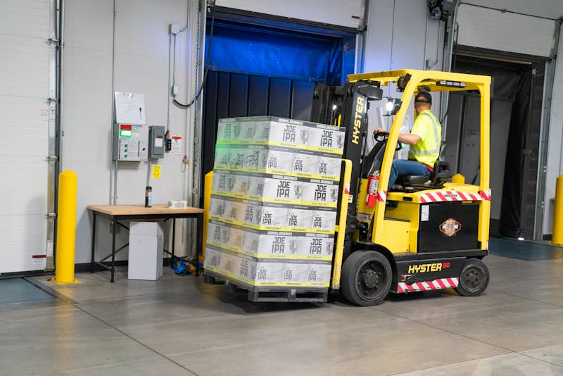 Warehouse worker operating a yellow forklift moving freight