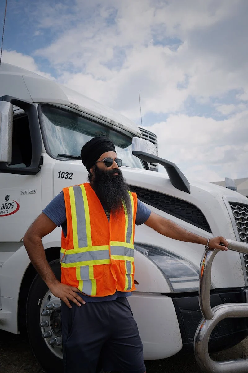 Truck driver in safety vest standing beside a white semi truck